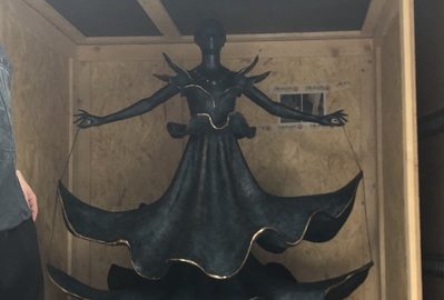 A tall bronze Dalí dancer sculpture crated inside the moving truck